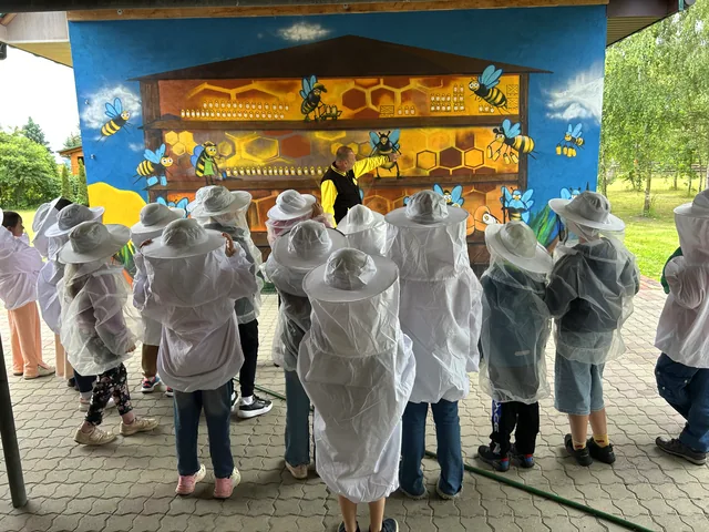 Dzieci przy graffiti edukacyjnym na ścianie pasieki